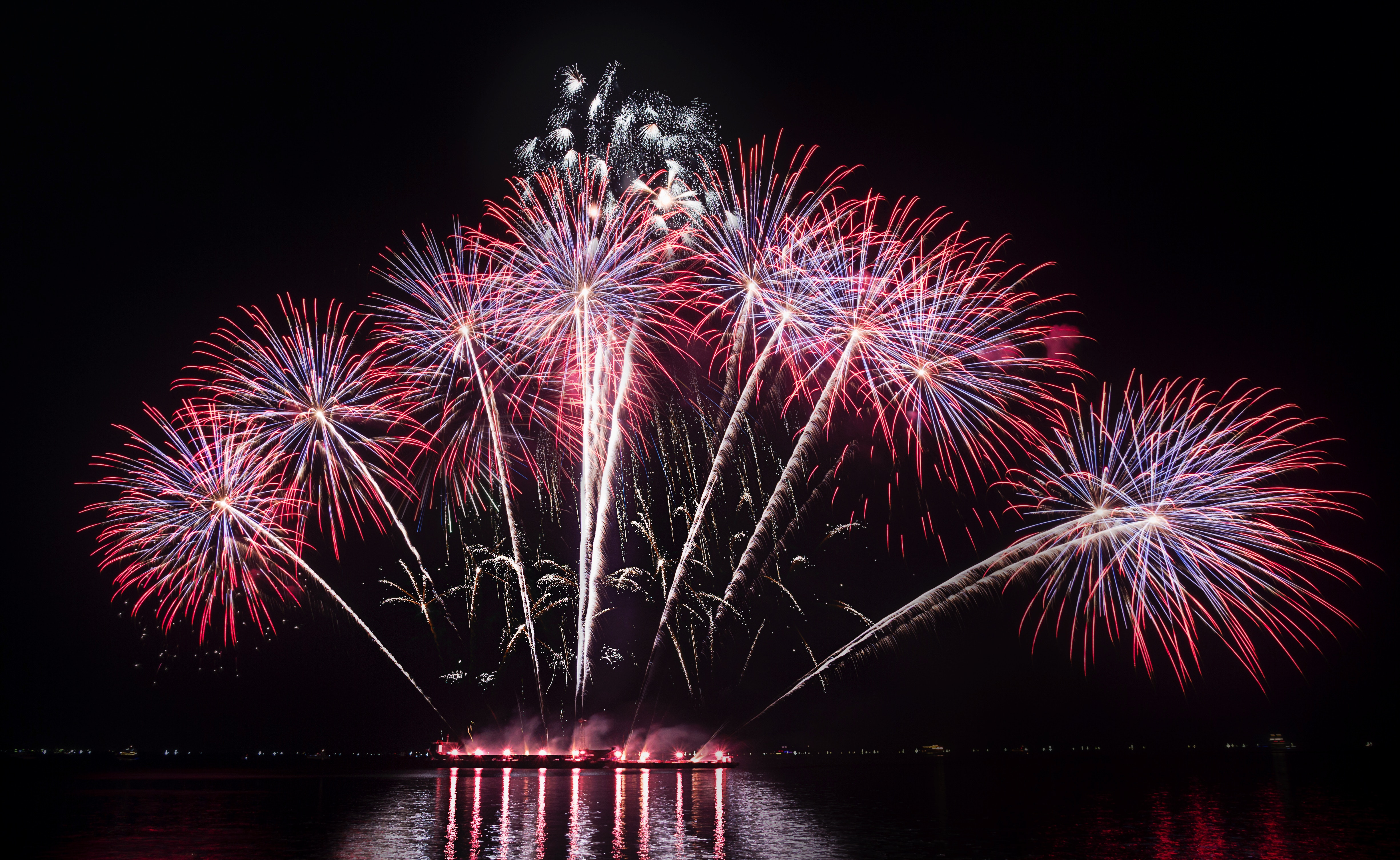 Red fireworks over the water with a night sky background